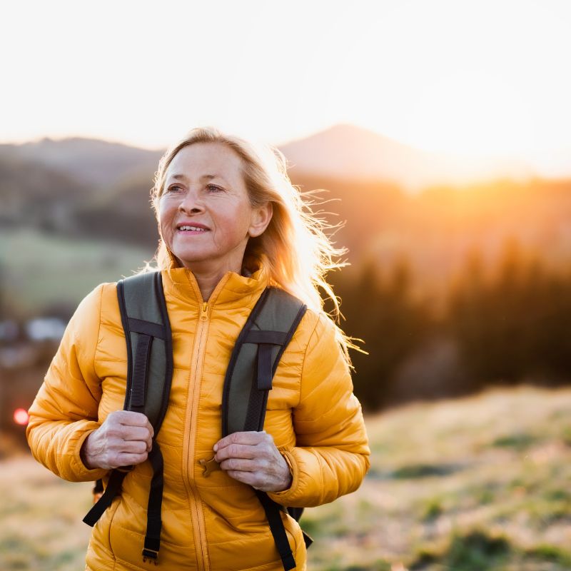 Woman hiking outdoors at sunset with backpack